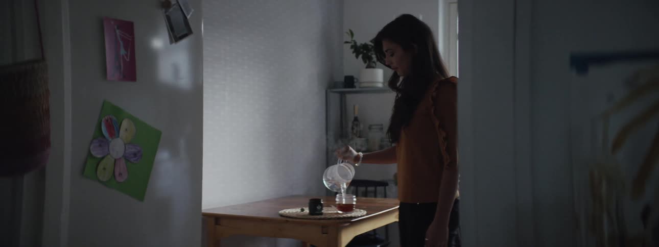 A woman pours steaming water into a teacup in a house with hand drawn art