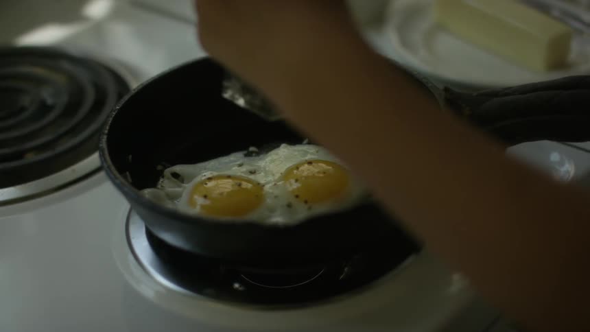 A person cooks fried eggs in a kitchen
