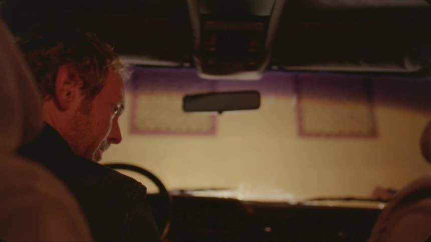 A man drives up to a building then looks to the person next to him