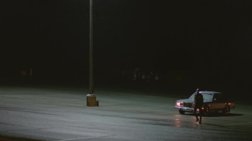 A man leaves his car and walks across the parking lot