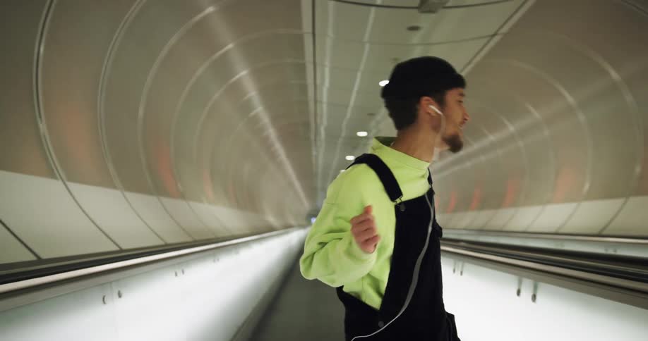 A man listens to music and dances in a tunnel