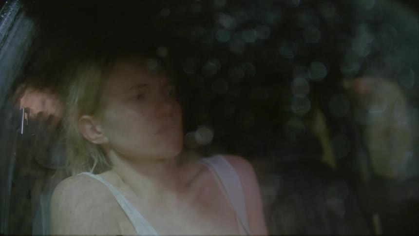 A woman is sitting behind glass as it rains