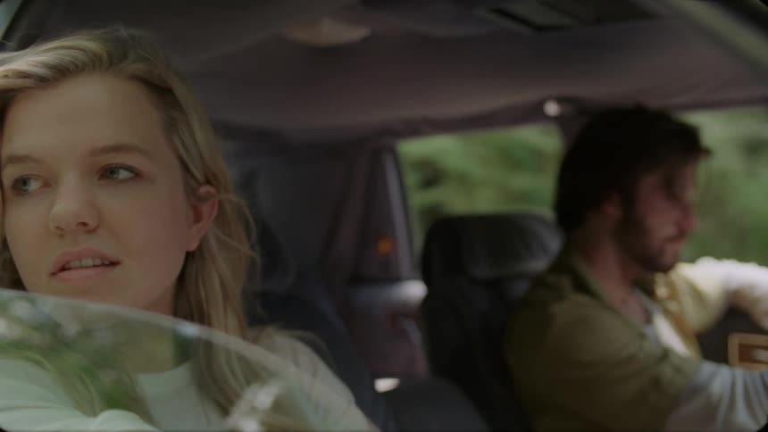 A man and woman are sitting in a car the woman is looking out the window