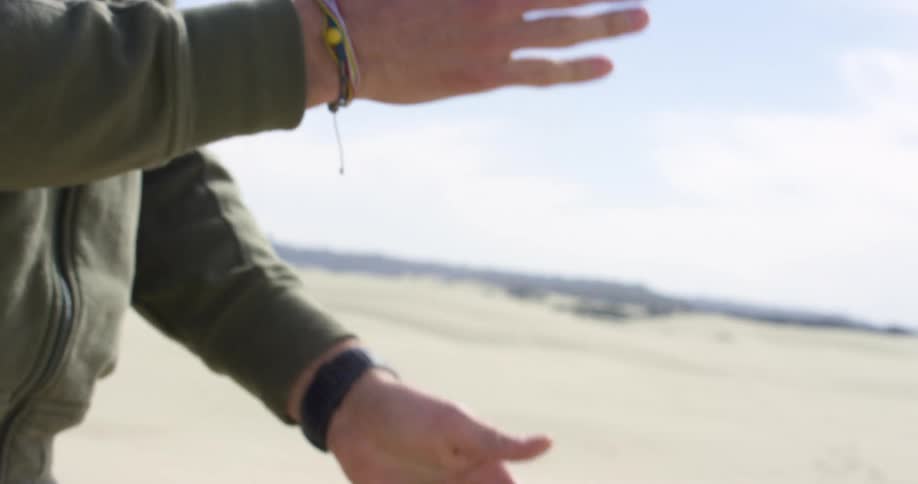 A man picks up sand and drops it and wipes his hands together