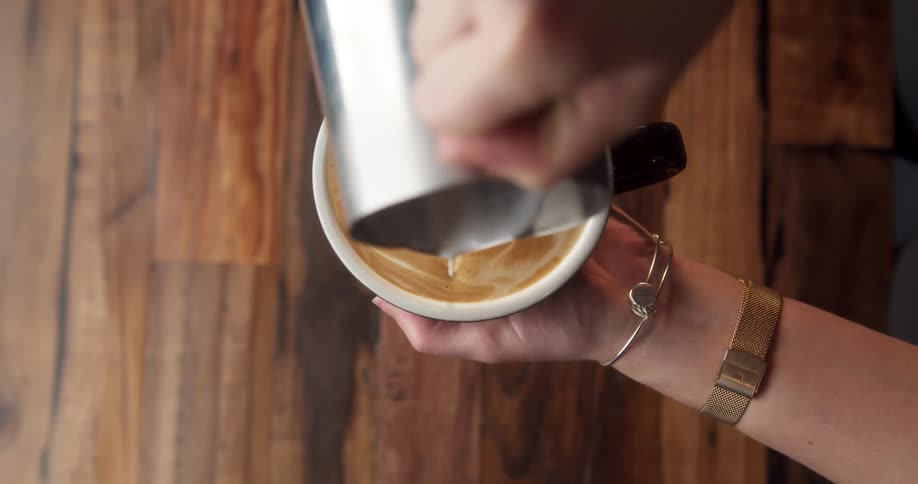 A person is pouring a drink in a cafe