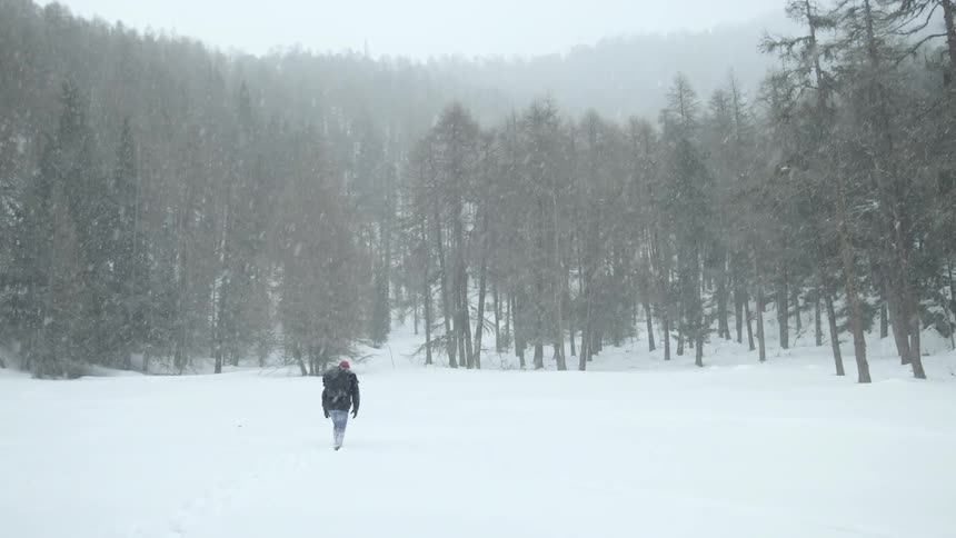 A man struggles through deep snow in a forest