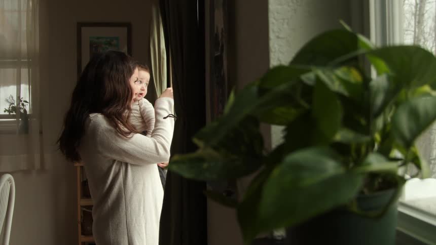 A mother holds her son by the window