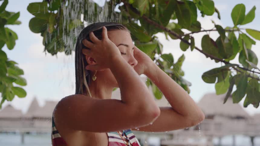 A white woman in a swimsuit showers outdoors at a resort