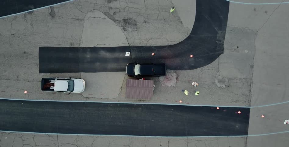 Cars are driving in a parking lot where people are walking