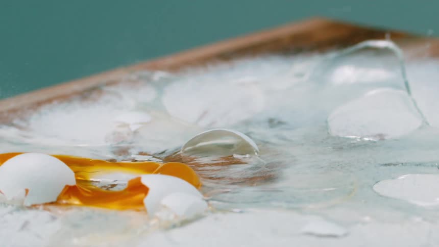 An egg falls and cracks all over a flour covered cooking surface