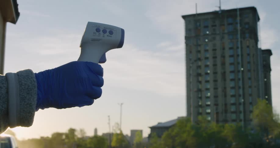 A person points a thermometer outside