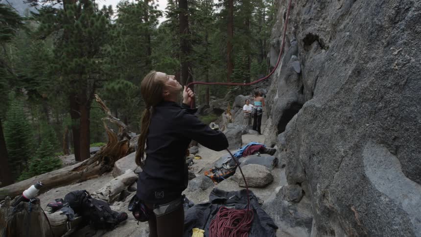 A woman near a cliff adjusting rope