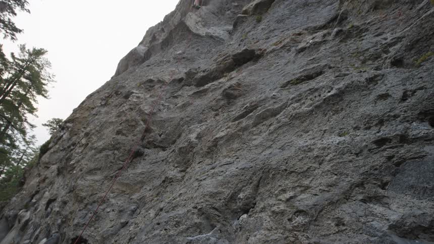 A man rock climbs as a woman holds the rope
