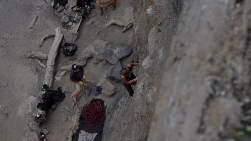 Woman climbs vertical rock wall using climbing equipment
