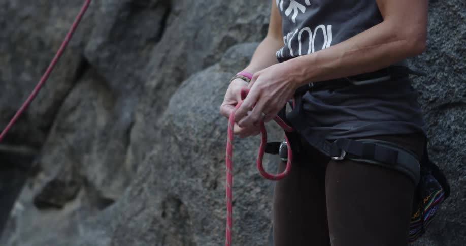 Rock climber ties the rope on the harness