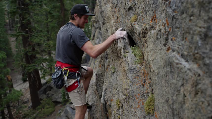 A white man climbs a rock face