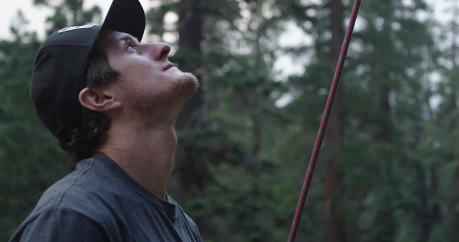 A man pulls on a climbing rope while looking up