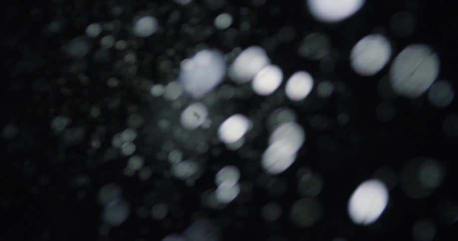 Falling snow out of focus at night