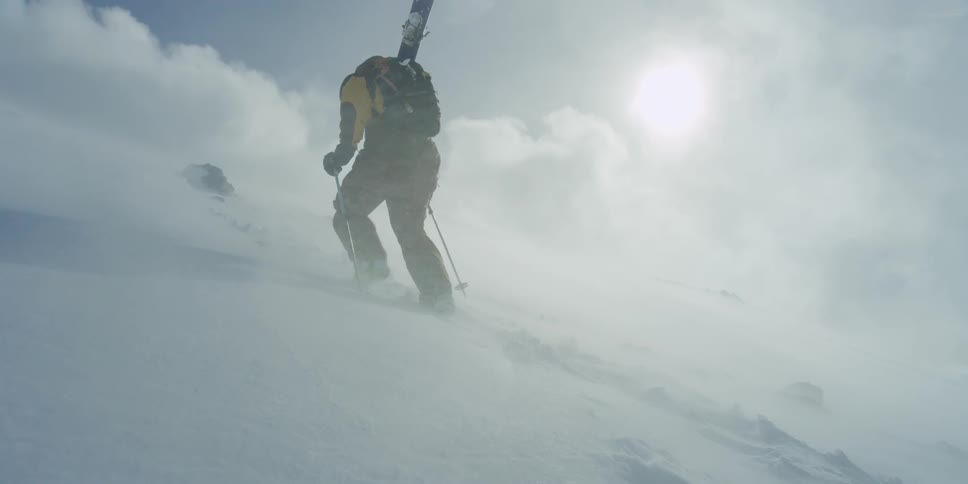 A man hikes up through the snow in vicious wind