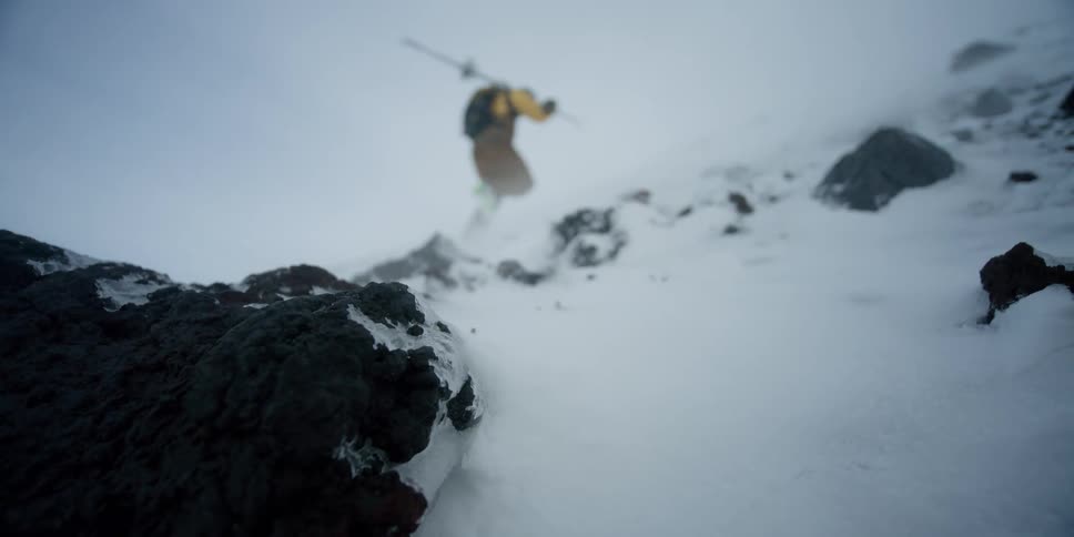 A hiker walking up a snowy mountain through fiercely blowing snow