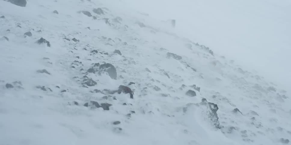 A snowstorm howls over rocks