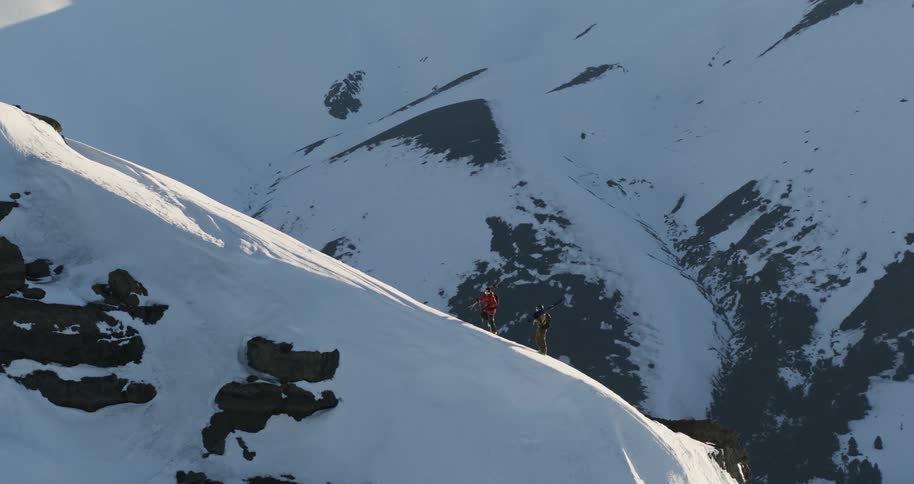 Aerial of mountain climbers walking up the side of a snowy mountain