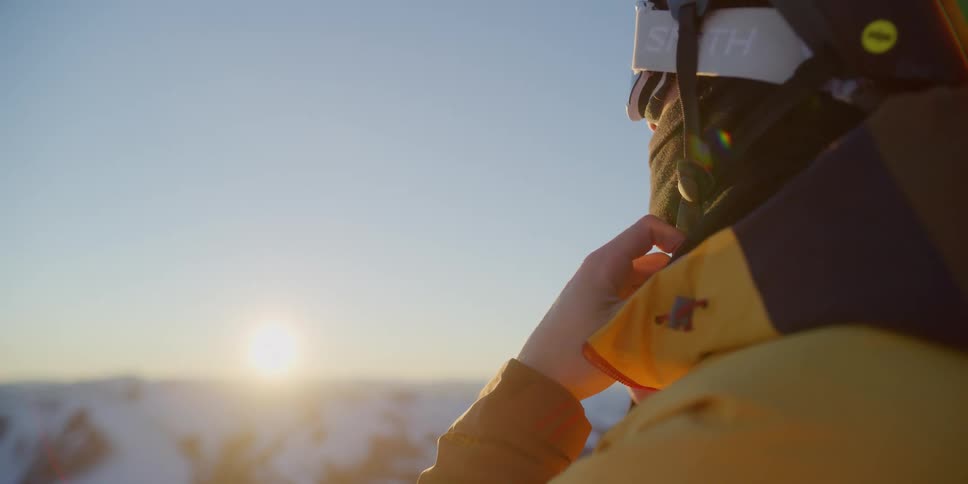 Skier adjust his helmet at sunset