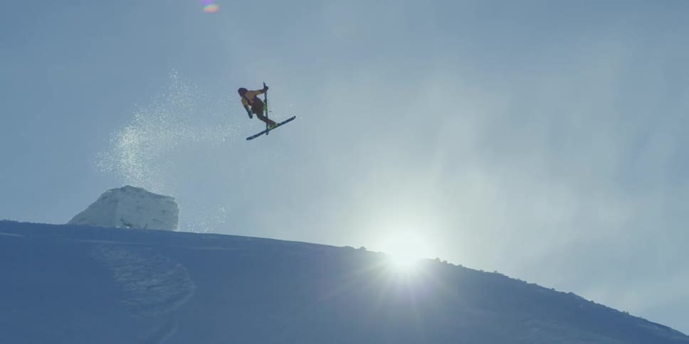 A skier jumps and spins in front of the sun