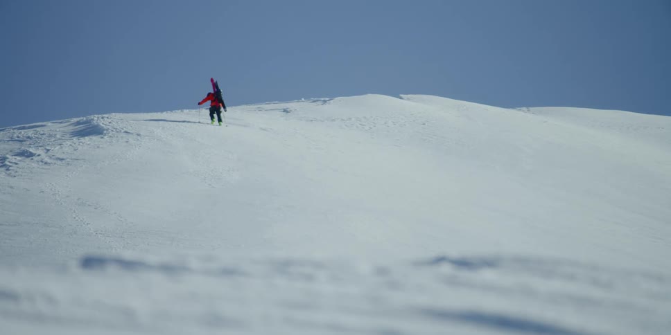 A skier hikes alone up a snow covered mountain
