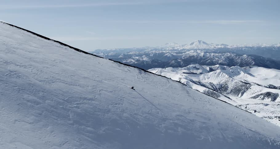 Aerial of a skier on a steep ridge in front of a massive valley