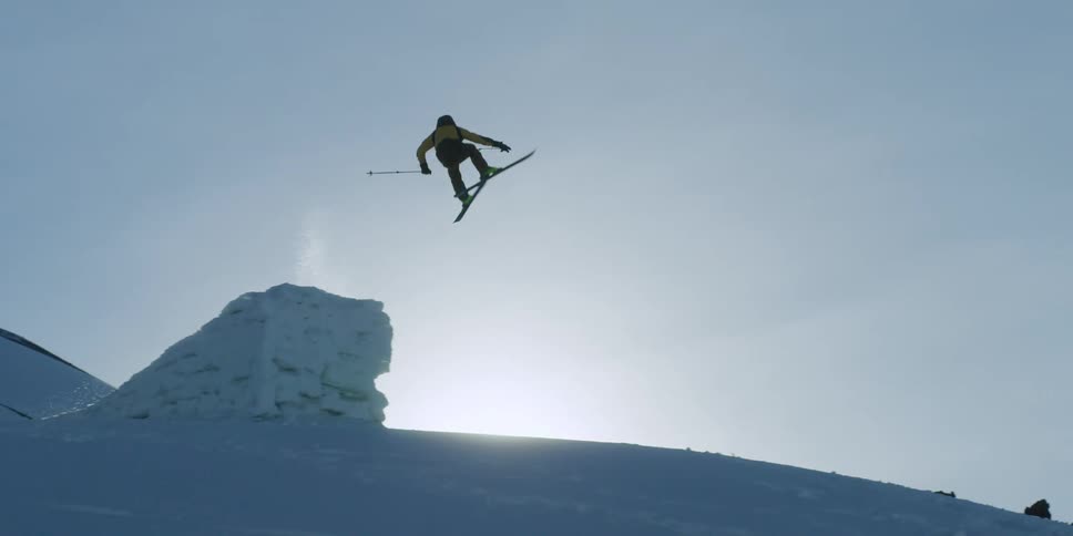 A skier jumps a ramp on top of a snow covered mountain slope