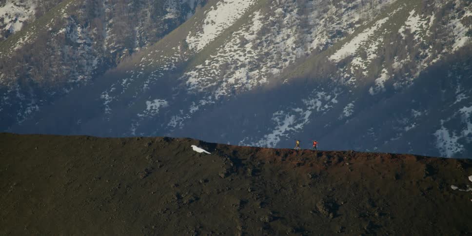 Skiers walk on the edge of a volcanic ridge
