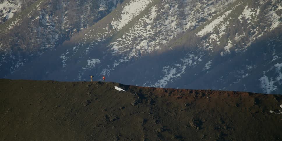 Two people hike along a ridge in the mountains in surreal light