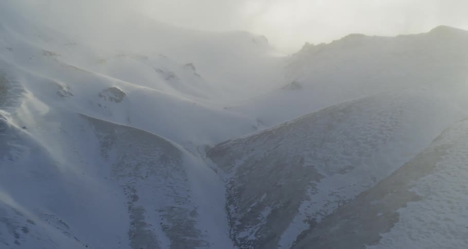 Aerial view of mountain range covered in snow and mist