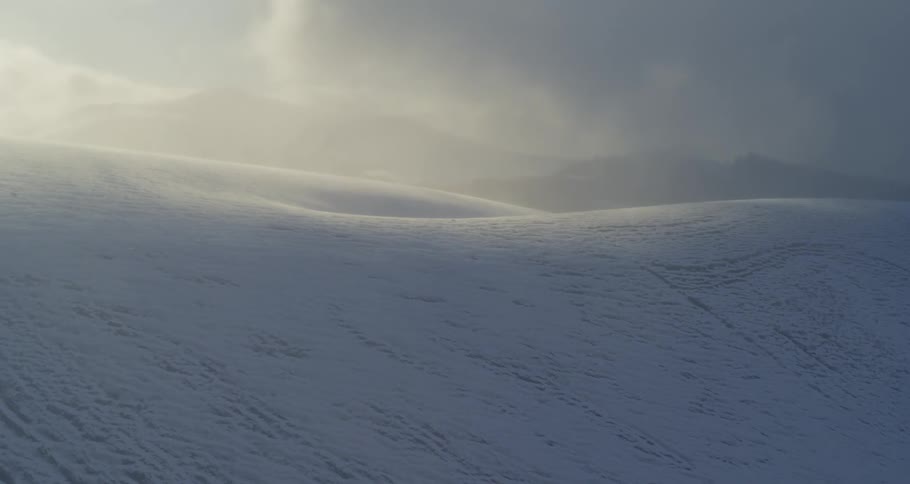 Aerial push over surreal rolling winter landscape at sunset