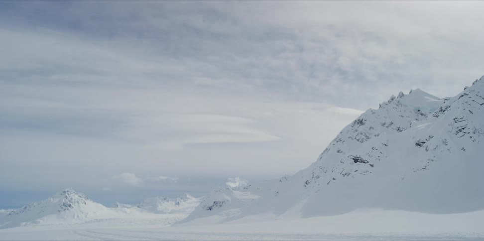 Clouds pass over a mountain peak covered in snow timelapse