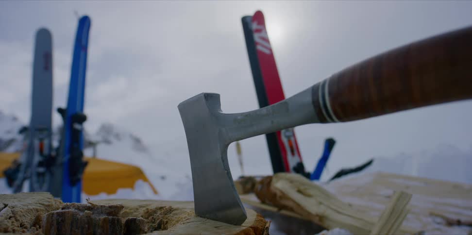 An axe is in a log near skis in the snow, timelapse