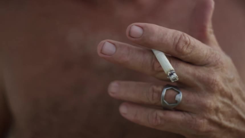 A person has a lit cigarette in one hand