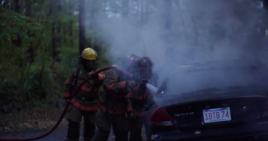 Three firefighters put out a fire in a car