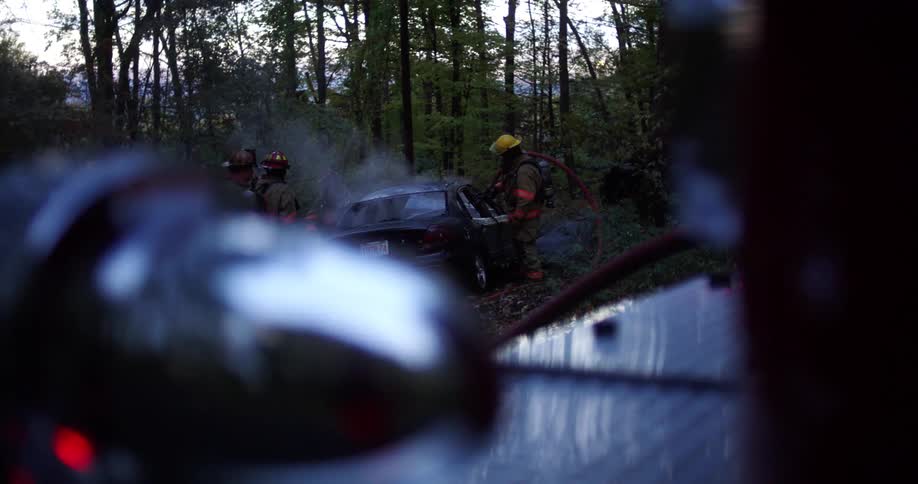 Firefighters examine a car after putting out a fire