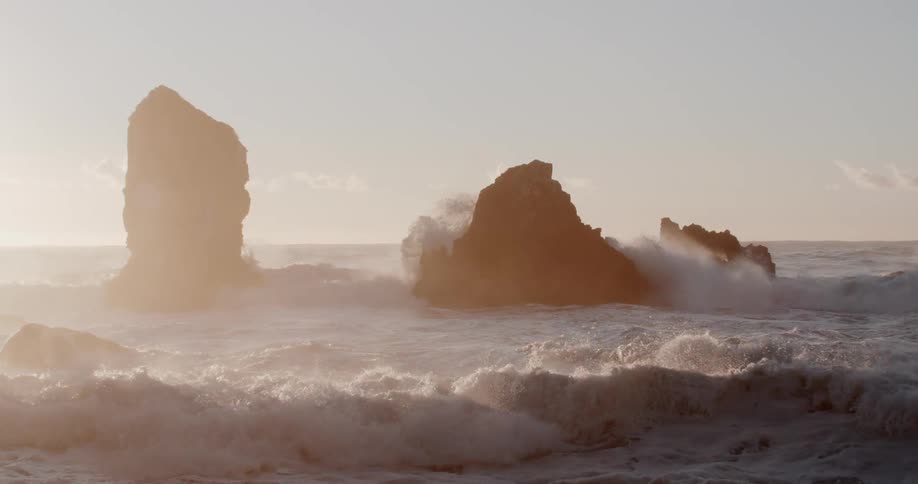 Ocean waves curl and splash as they break against the rocks