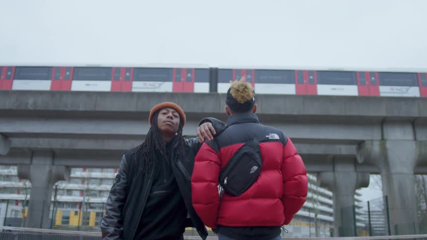 Two men stand outside as a train goes by