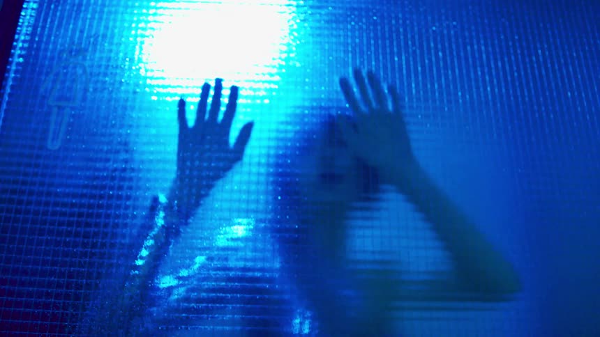 A woman dances behind glass