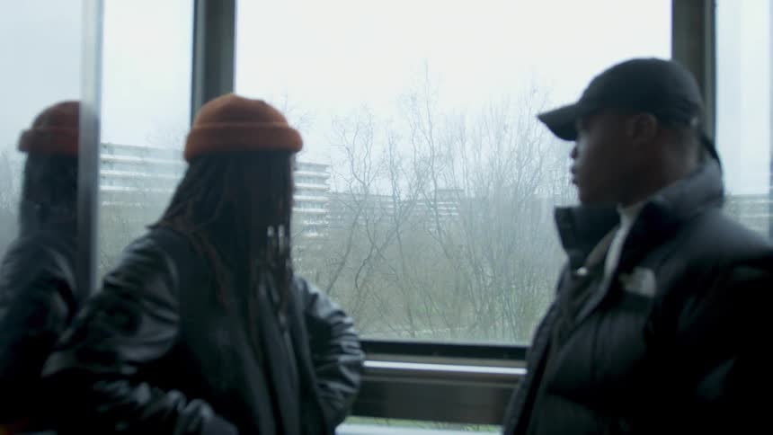 Black young men riding elevator with glass windows