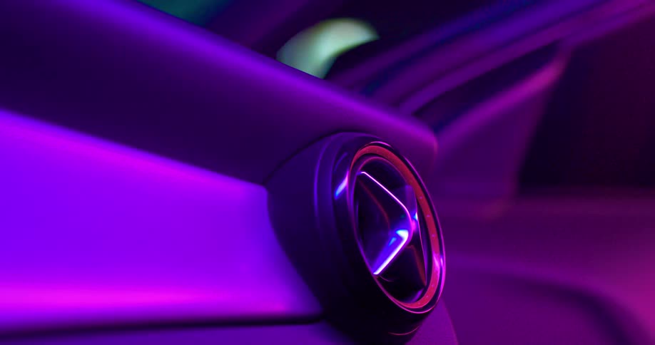 A car logo switches colors under blue and purple lights
