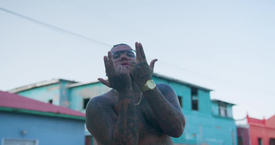 A man standing outside a housing complex makes hand signals