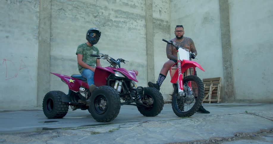 One man on an atv and another man on a dirt bike sit and relax