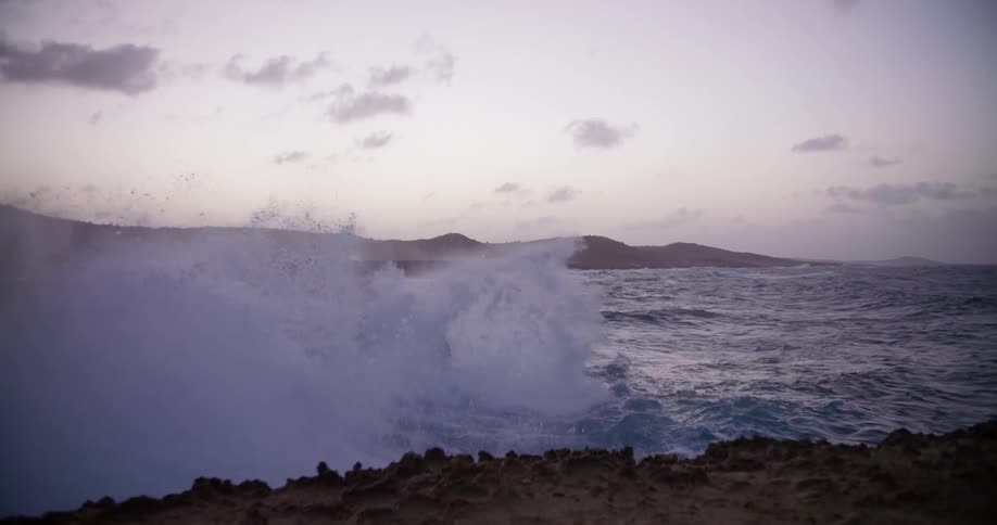 Waves crash against rocky shore at dusk