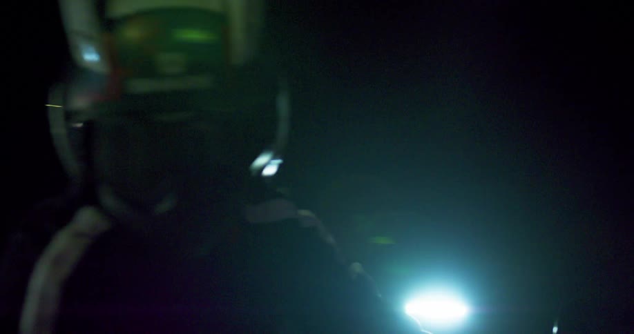 Person in full helmet rides motorcycle at night