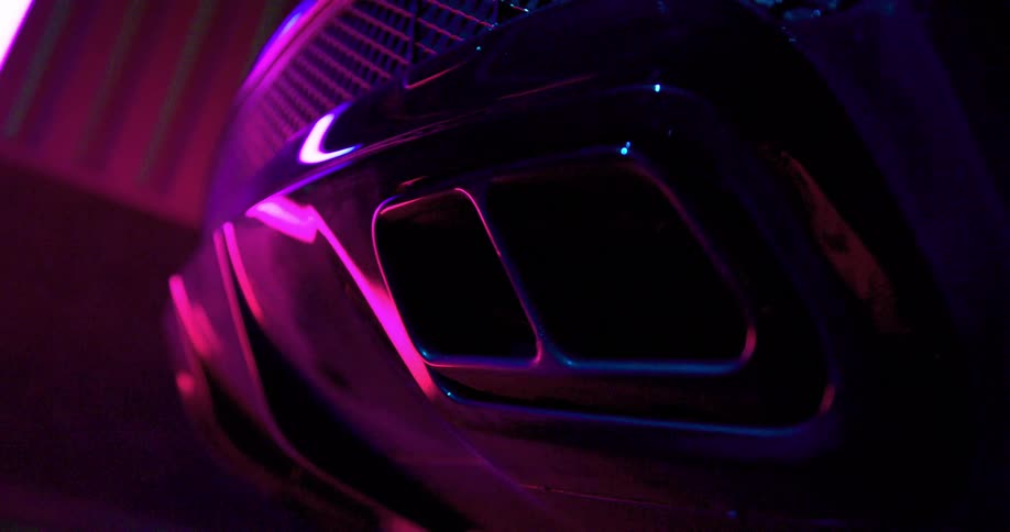Colorful neon lights reflection on car bumper on a dimly lit room